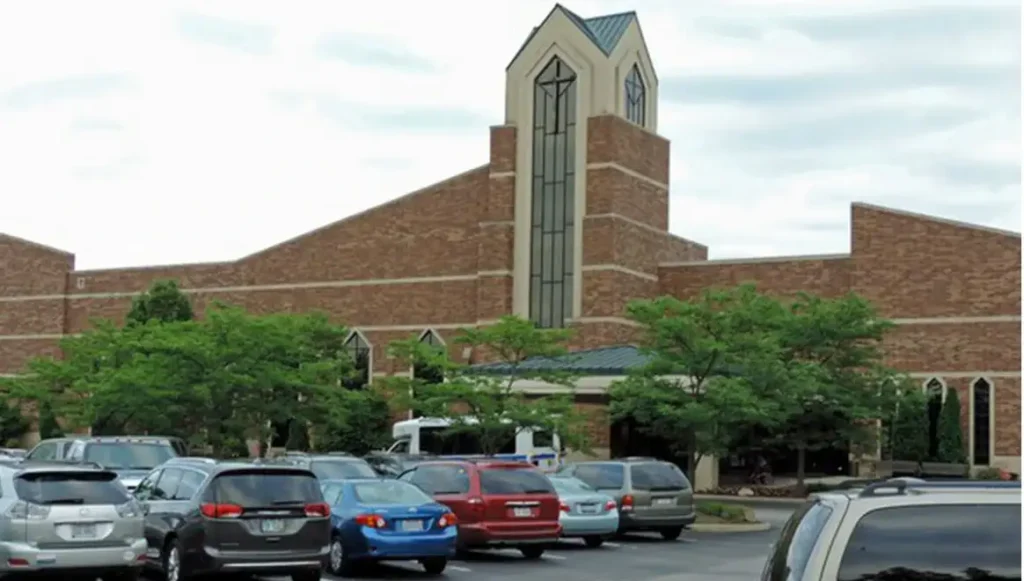 Exterior view of a church with a large parking lot, highlighting factors in church parking construction cost.