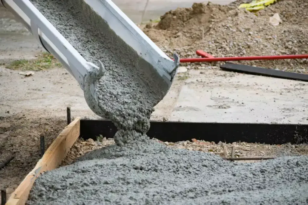 Concrete being poured from a chute into a formwork at a construction site.