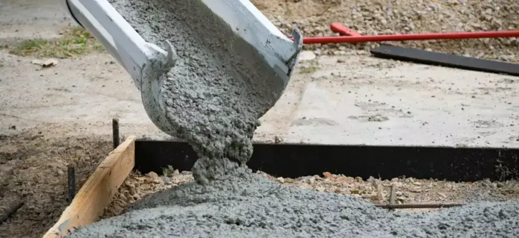 Concrete being poured from a chute into a formwork at a construction site.