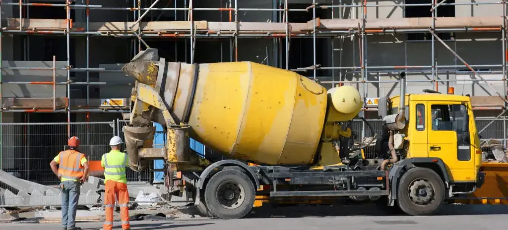 A yellow 10-yard concrete truck at a construction site with two workers nearby.