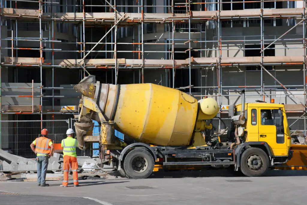 A yellow 10-yard concrete truck at a construction site with two workers nearby.