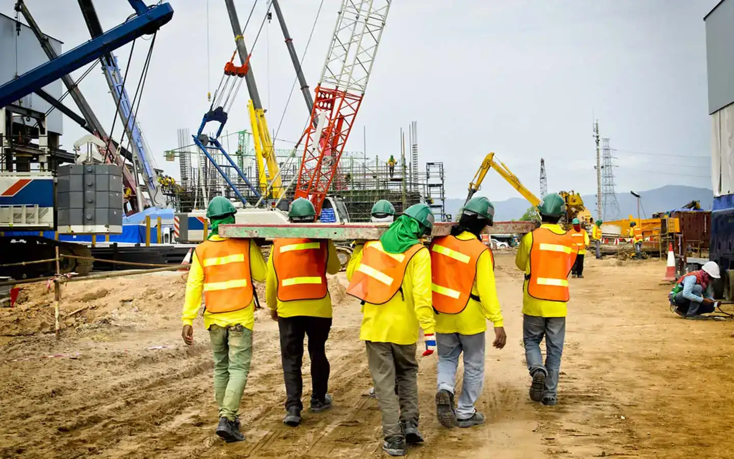 Construction workers walk along a dirt road, showcasing their commitment to quality and professionalism.