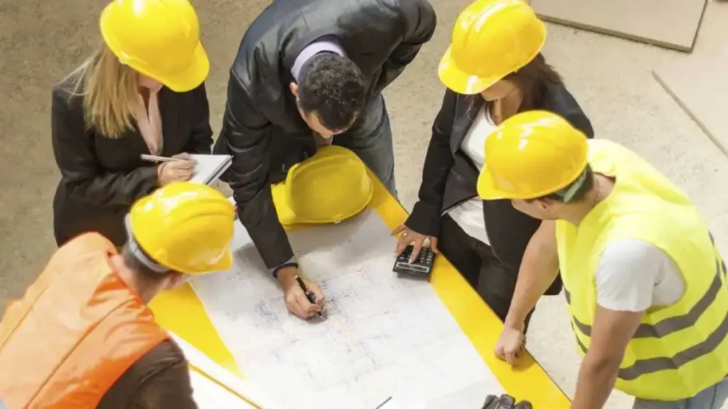 Construction workers in hard hats and safety vests diligently work on a project.