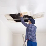 A man repairing ceiling drywall, showcasing home improvement skills and attention to detail.