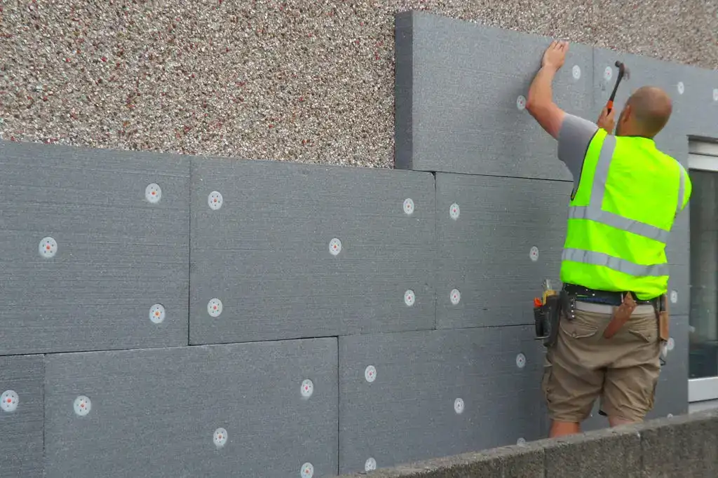 Installing external wall insulation panels for energy efficiency and cost savings.