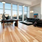 Light hardwood flooring in a modern office with large windows and minimal furniture.