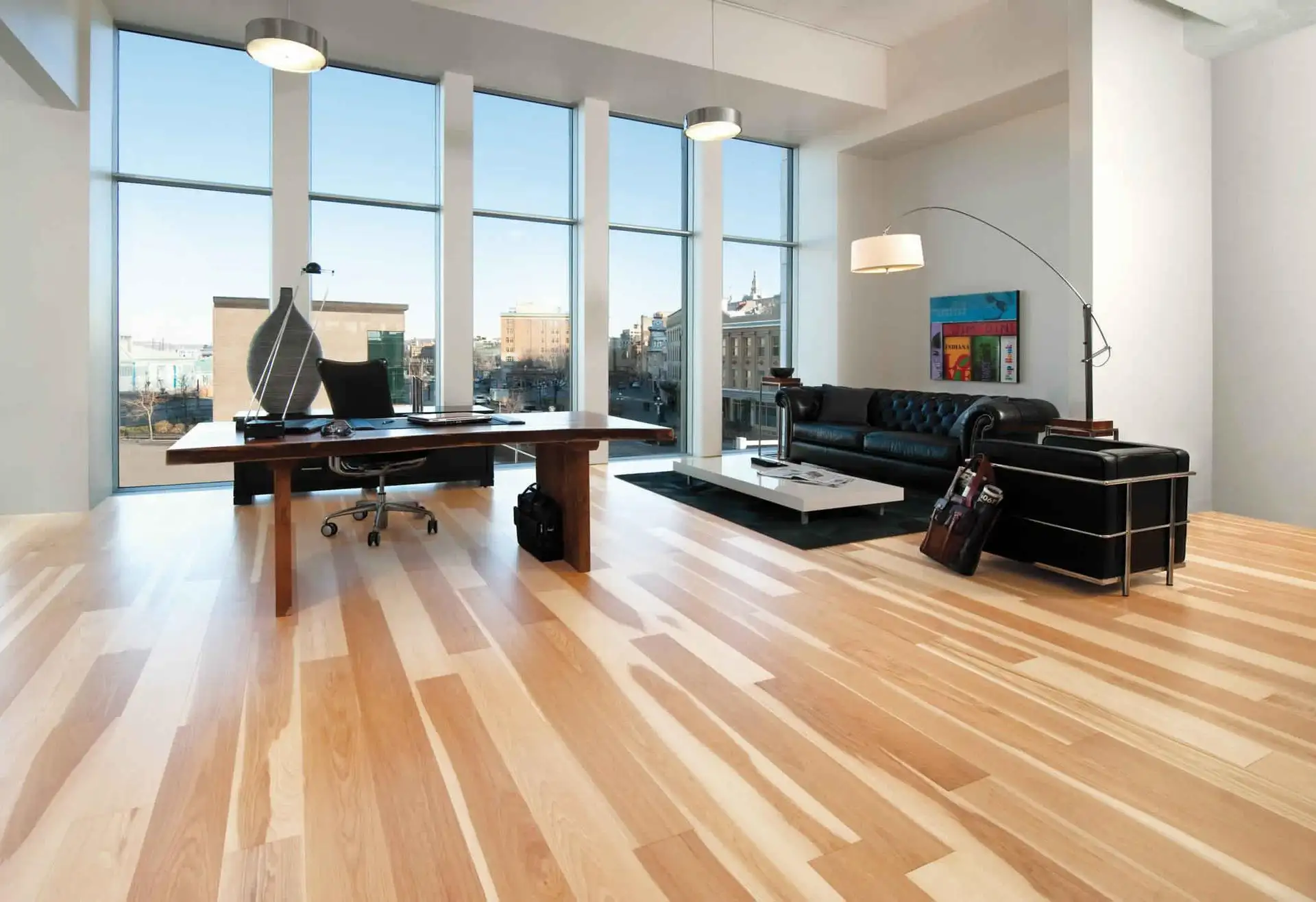 Light hardwood flooring in a modern office with large windows and minimal furniture.