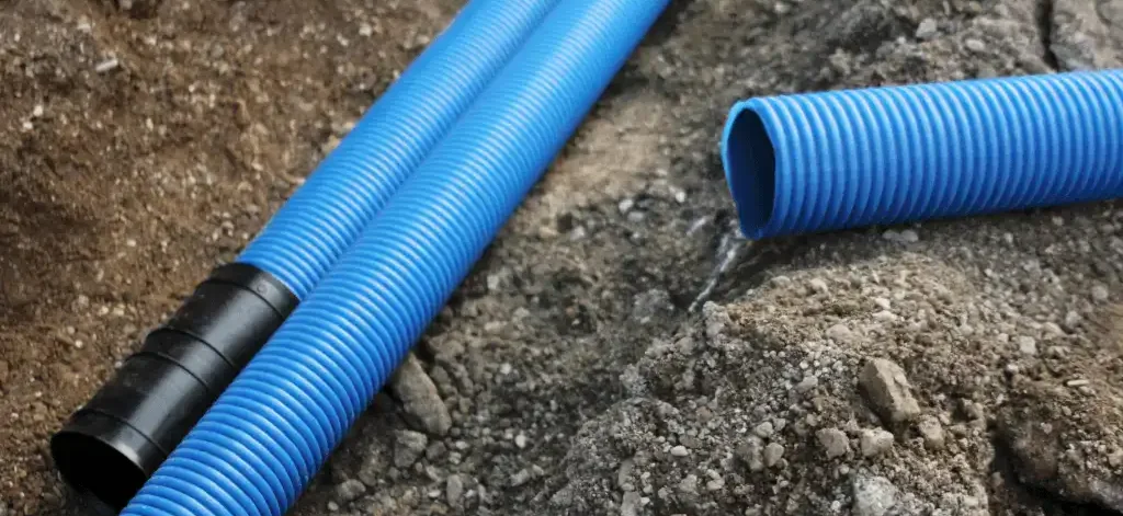 A blue pipe on the ground, part of the main water line installation.