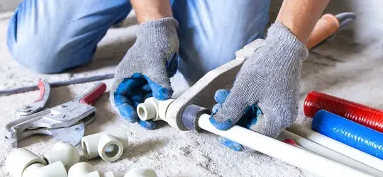  A man uses tools to work on a pipe while plumbing a 1,500 sq ft house.