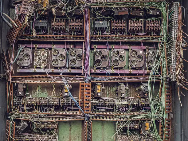 Old, cluttered electrical panel with exposed wires