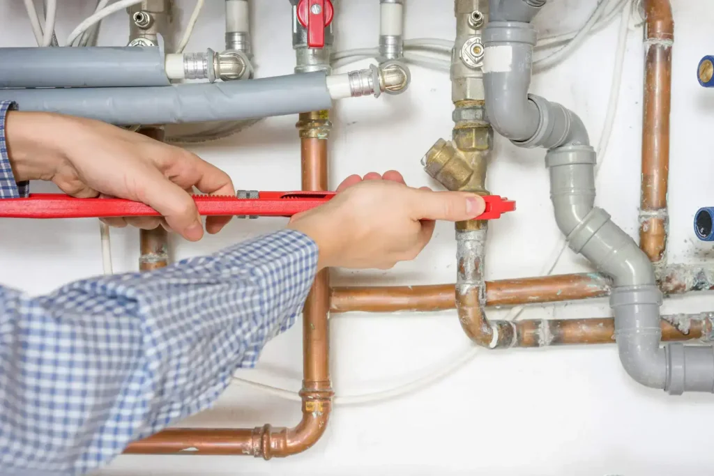 A person uses a red tool while doing plumbing repairs in a 1,500 sq ft house.