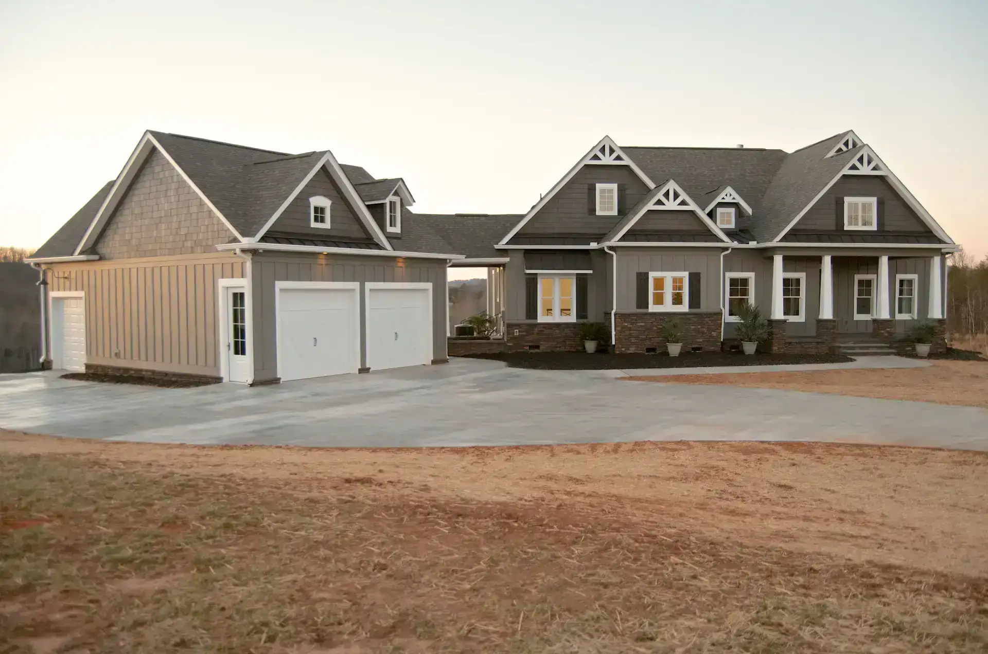 Large detached garage with dual white doors next to a craftsman-style house.