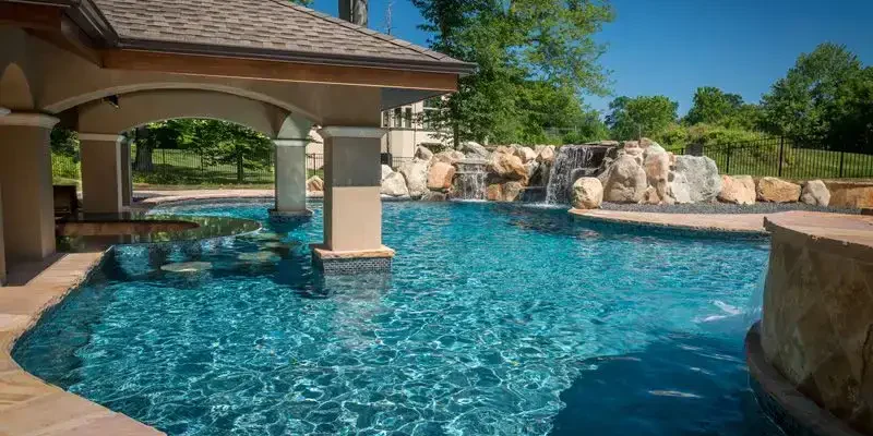 Luxury inground pool with a waterfall feature and poolside pavilion in Florida.